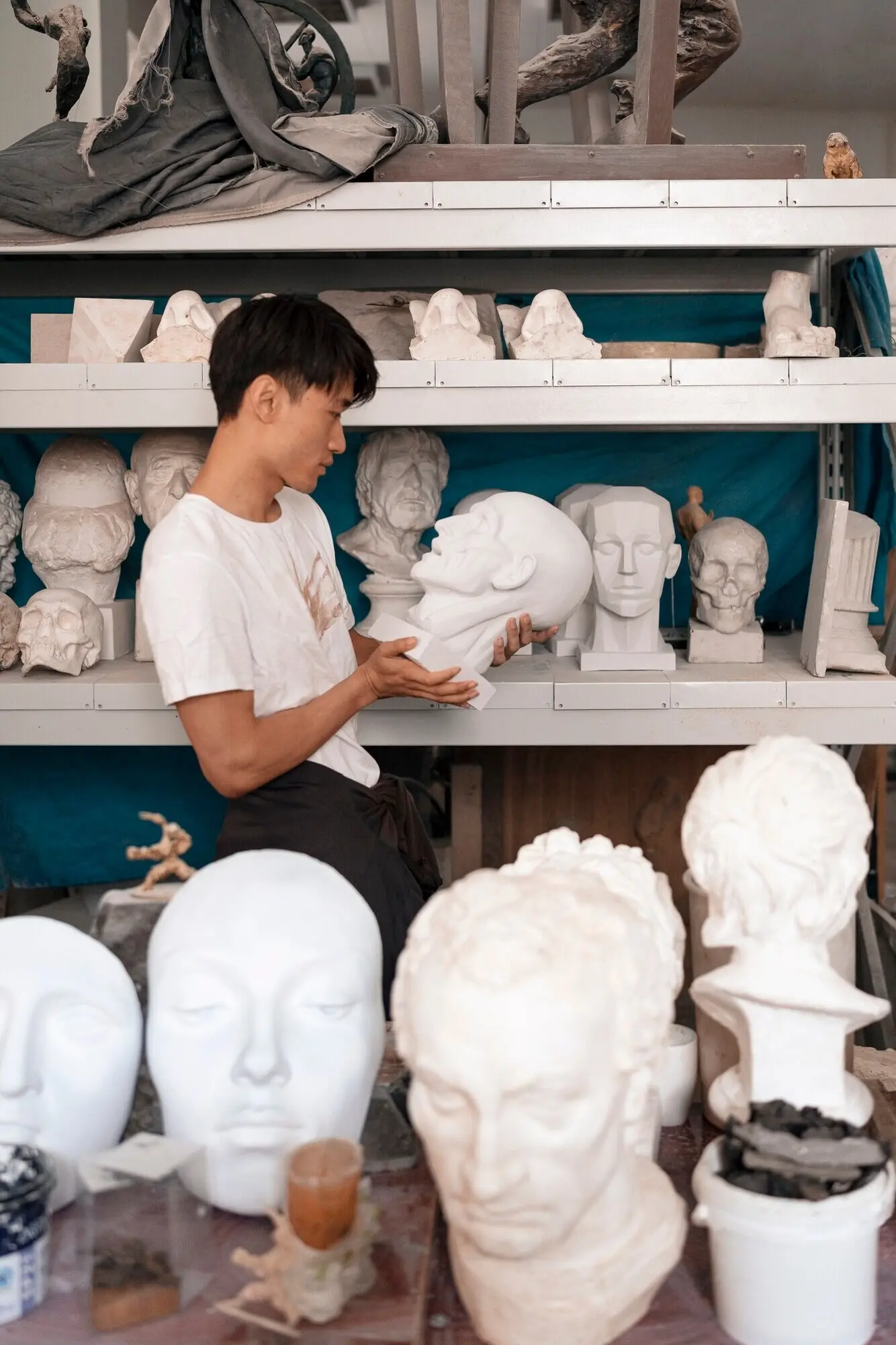 Seitenansicht eines Mannes, der eine Skulptur hält.