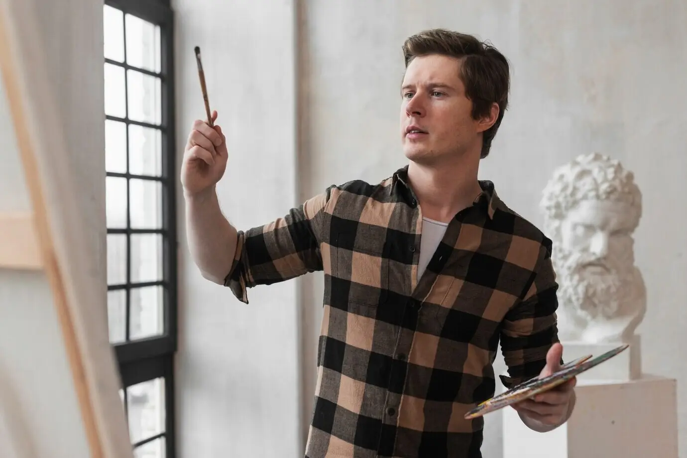 Junge/r Künstler/in beim Malen mit Pinsel auf Leinwand